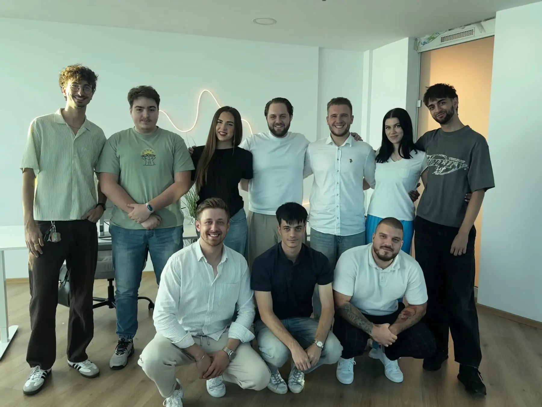 Ten team members posing for a group photo in an office, seven standing and three crouching in front.